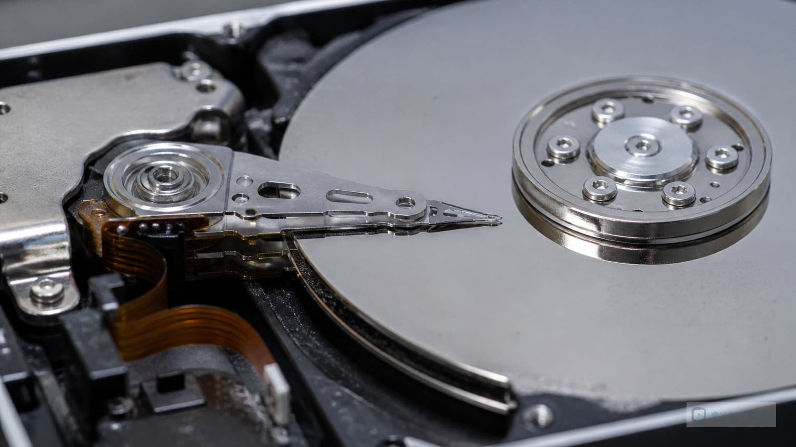 Close-up of an opened hard-disk platter and actuator arm, illustrating storage media relied on for recovery.