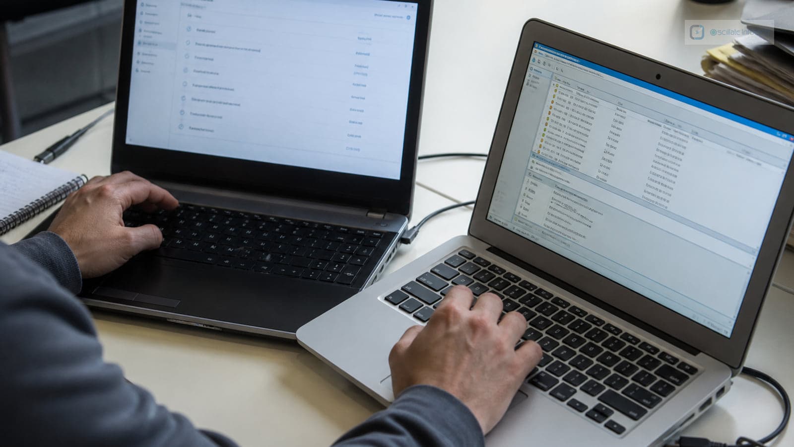 Technician viewed from behind at a desk with two unbranded laptops, printed release checklists and a rollout plan on a whiteboard.