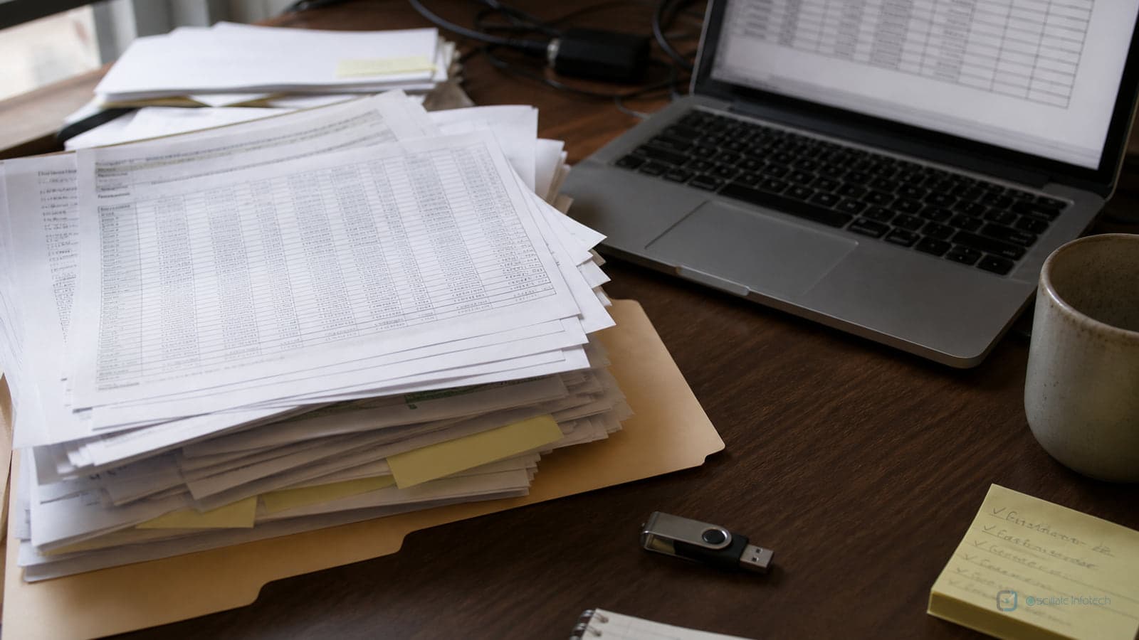 Top-down view of paper forms, a phone calculator and a pen on a wooden floor, illustrating a manual file process overloaded as production work.