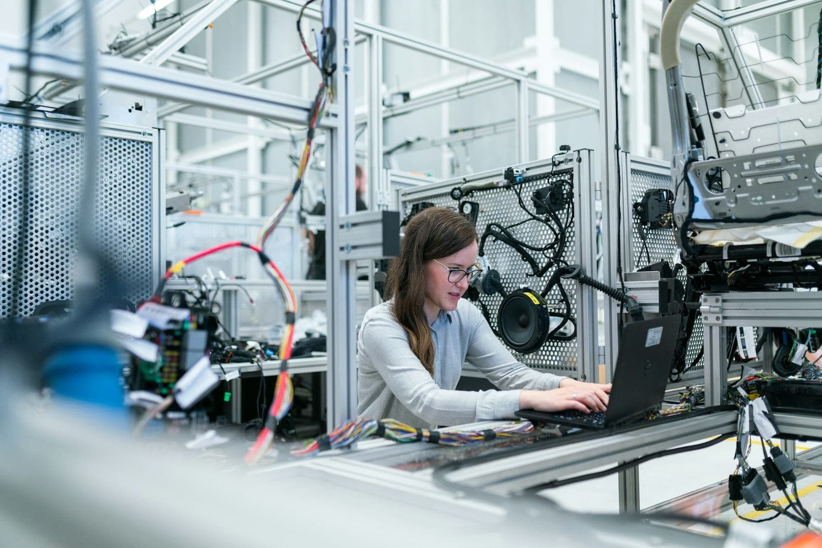 Engineer working on a laptop beside a production line